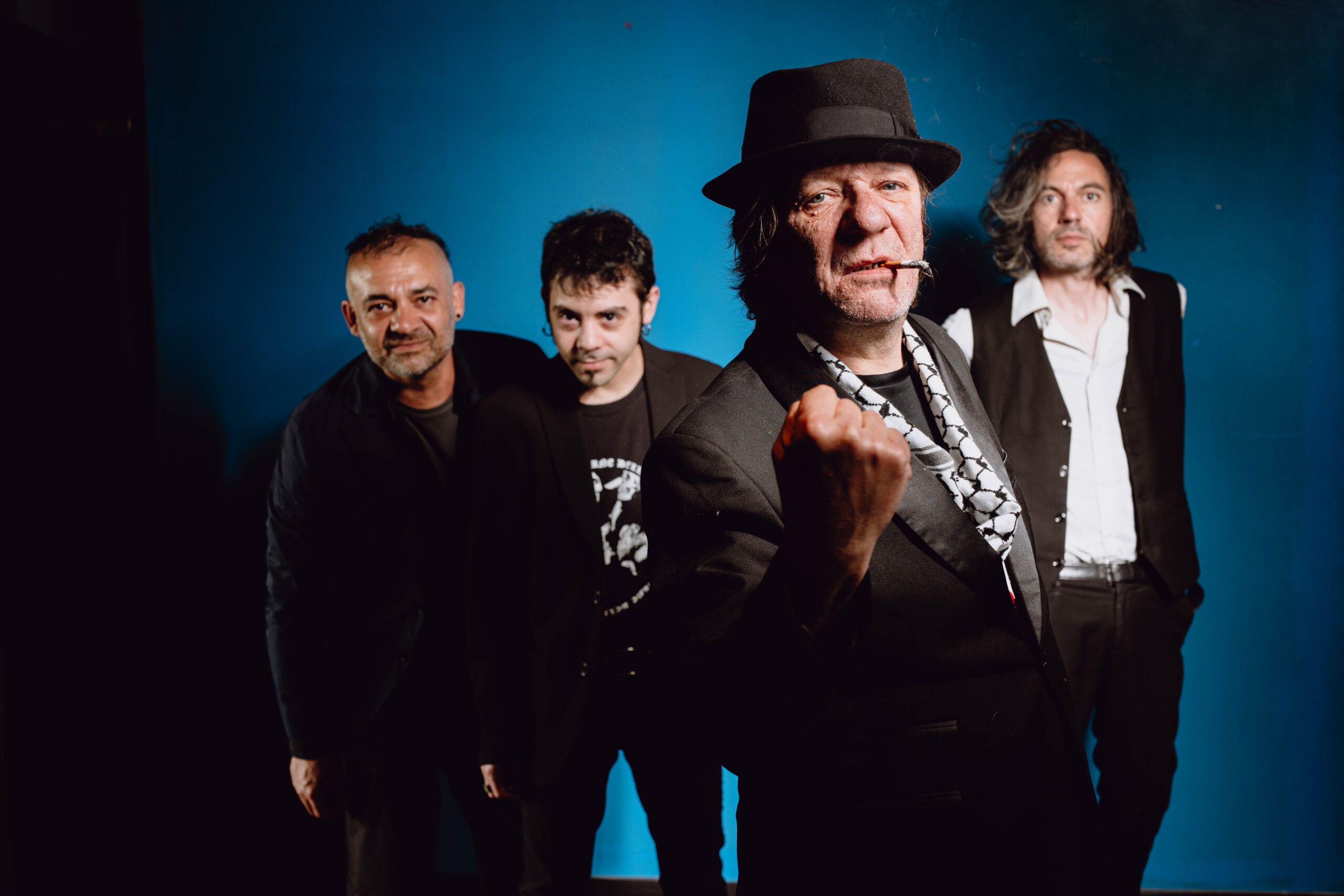Ritratto del gruppo musicale Pierpaolo Capovilla e i Cattivi Maestri su sfondo blu.