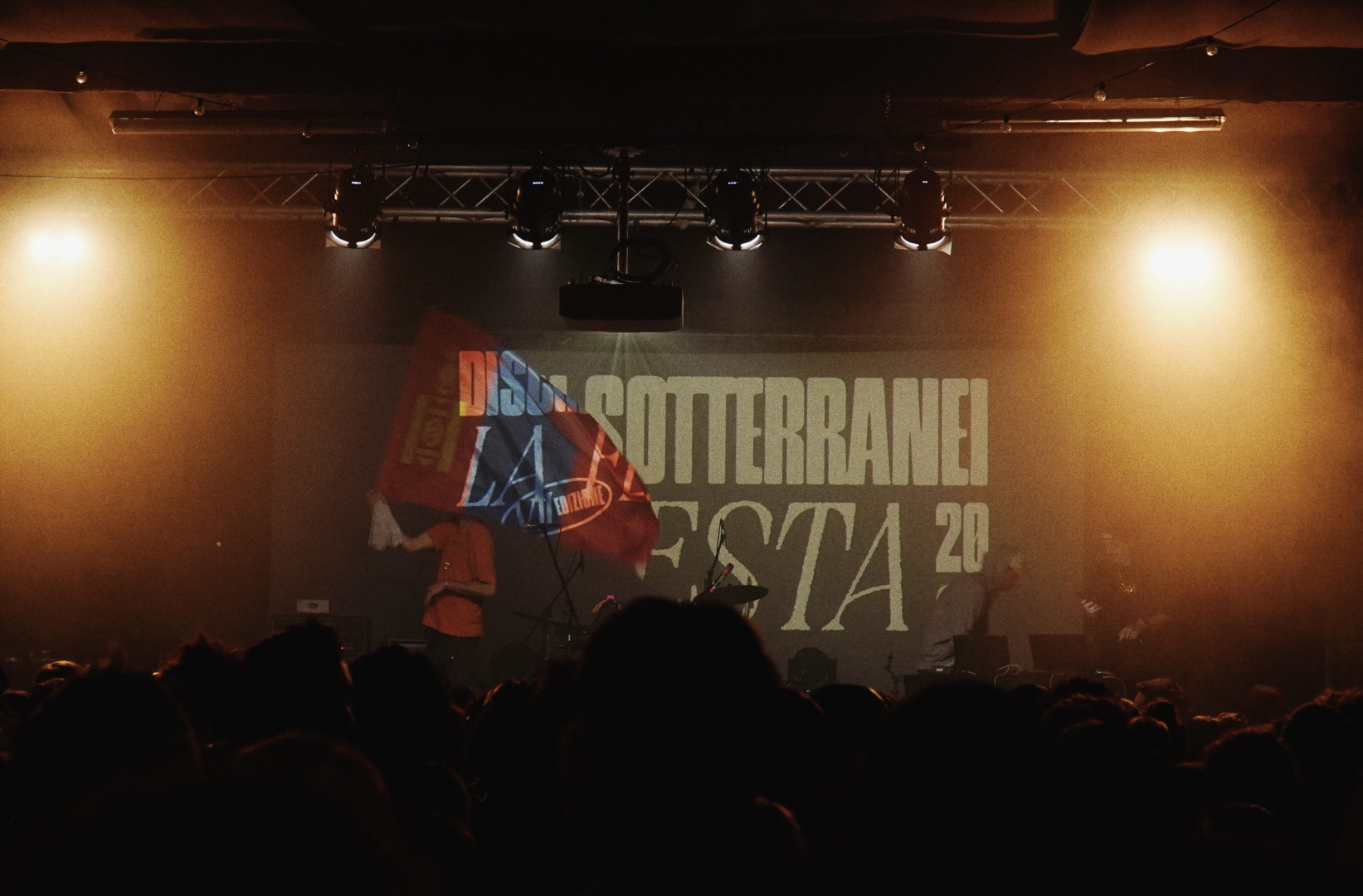 Un artista agita una bandiera sul palco durante l'evento Dischi Sotterranei - La Festa.